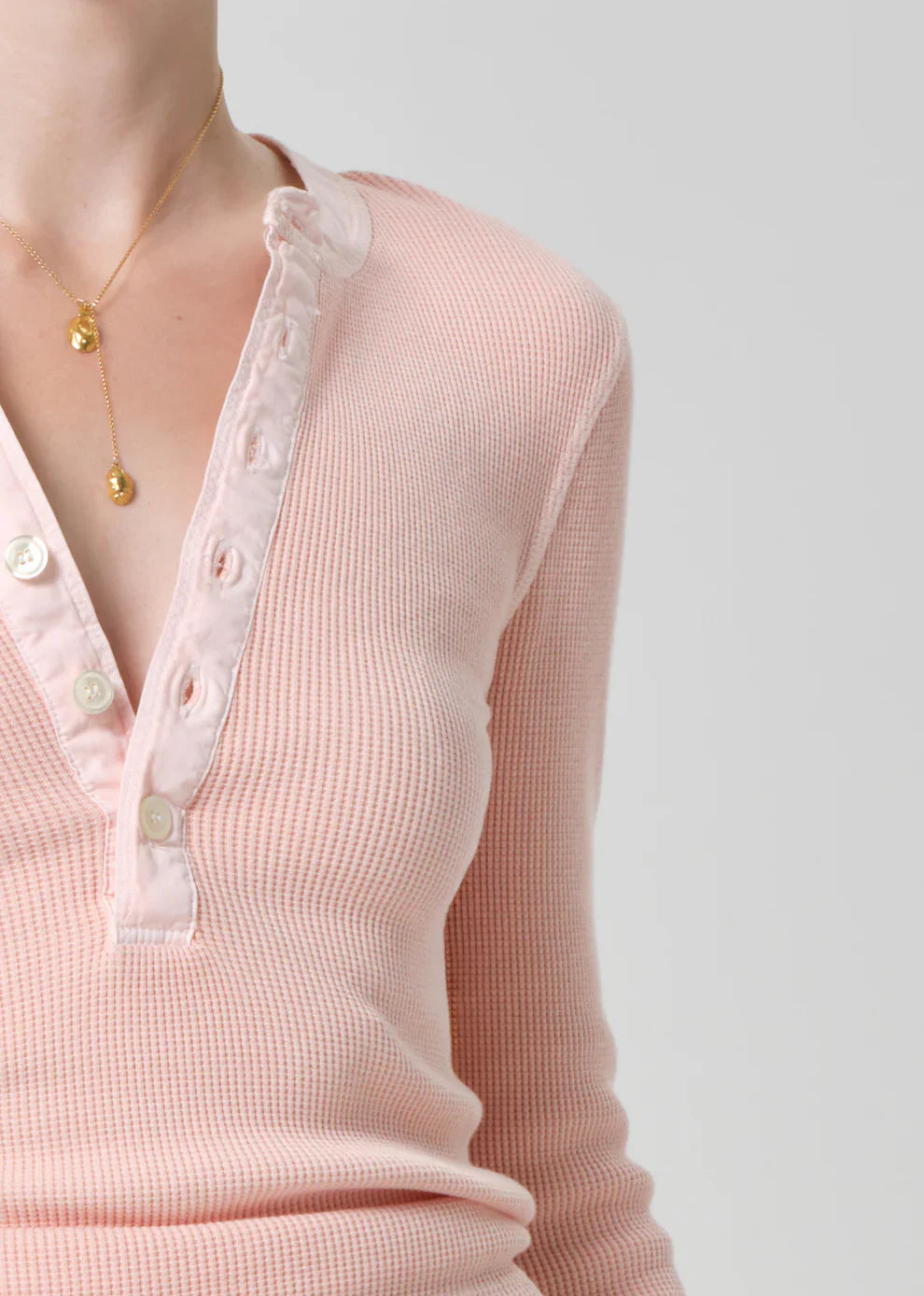Close-up of a pink ribbed sweater with lace trim on a plain background