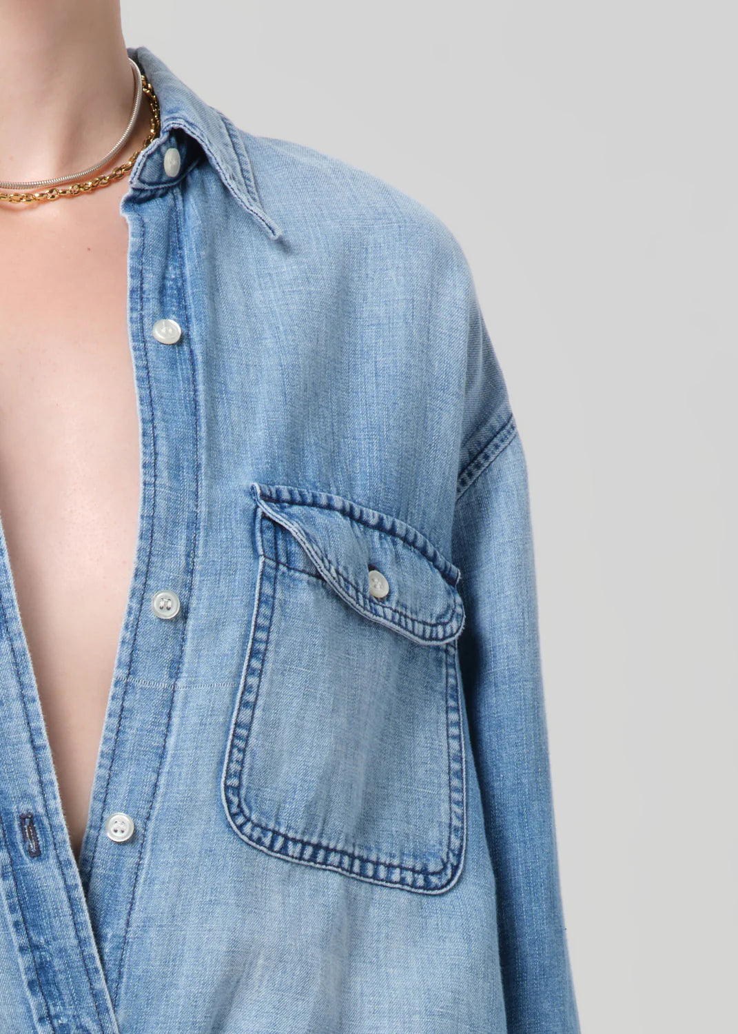 Blue denim shirt with a pocket on a plain background