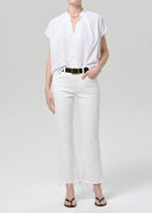 Person wearing a white shirt and white pants on a plain background