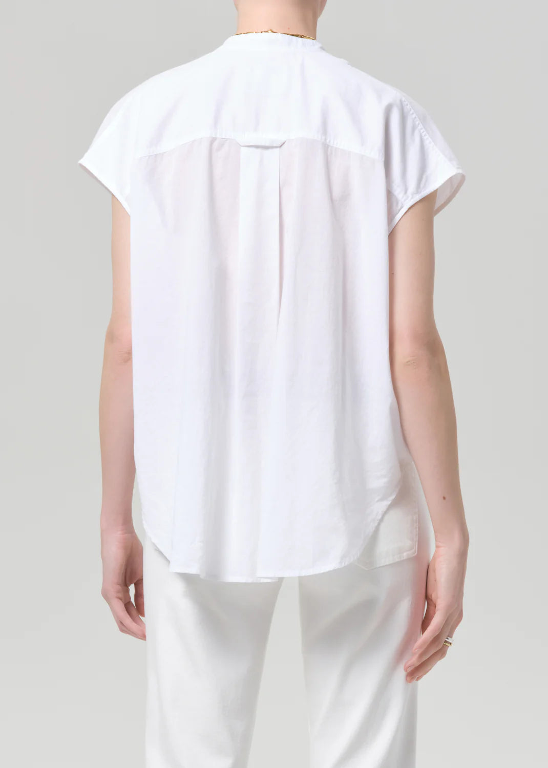 Person wearing a white sleeveless top and pants on a plain background