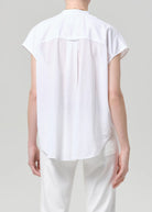 Person wearing a white sleeveless top and pants on a plain background
