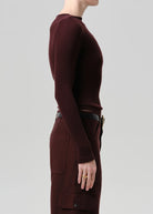 Person wearing a maroon long-sleeve top and pants on a light gray background