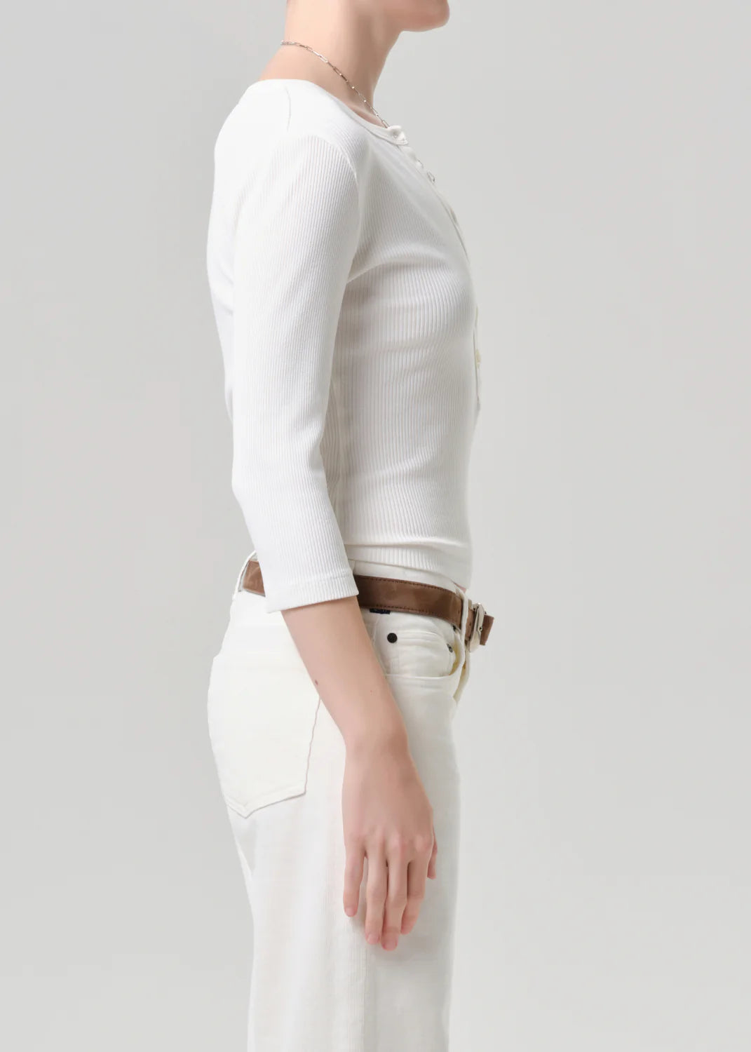 Person wearing a white long-sleeve top and white pants on a plain background