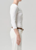 Person wearing a white long-sleeve top and white pants on a plain background