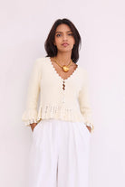 Woman wearing a cream-colored top with lace details on a white background