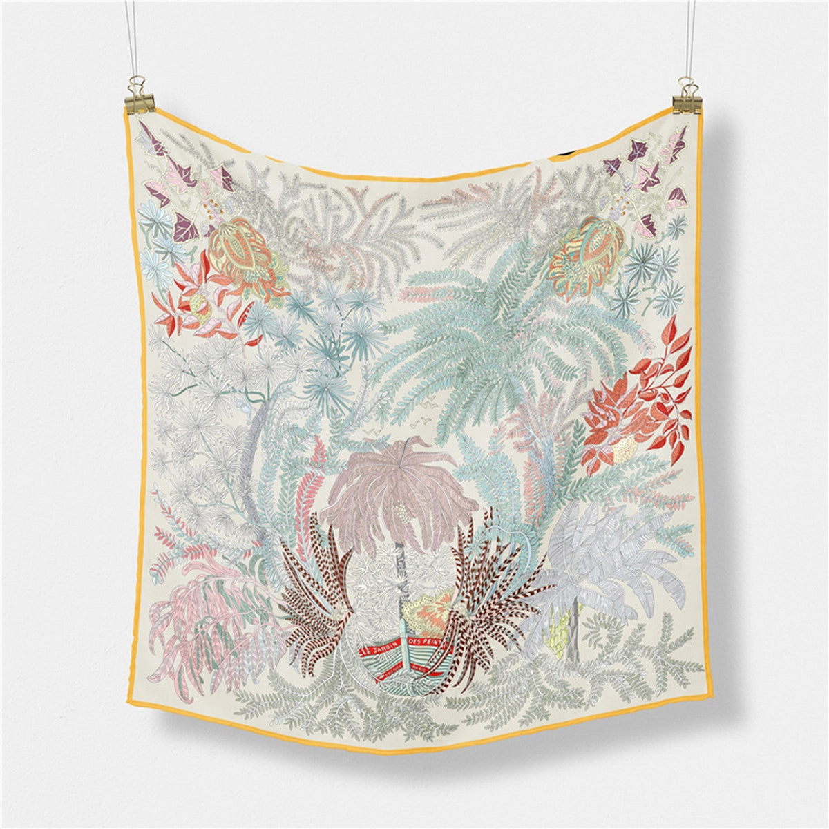 Decorative scarf with floral and leaf patterns hanging on a white background