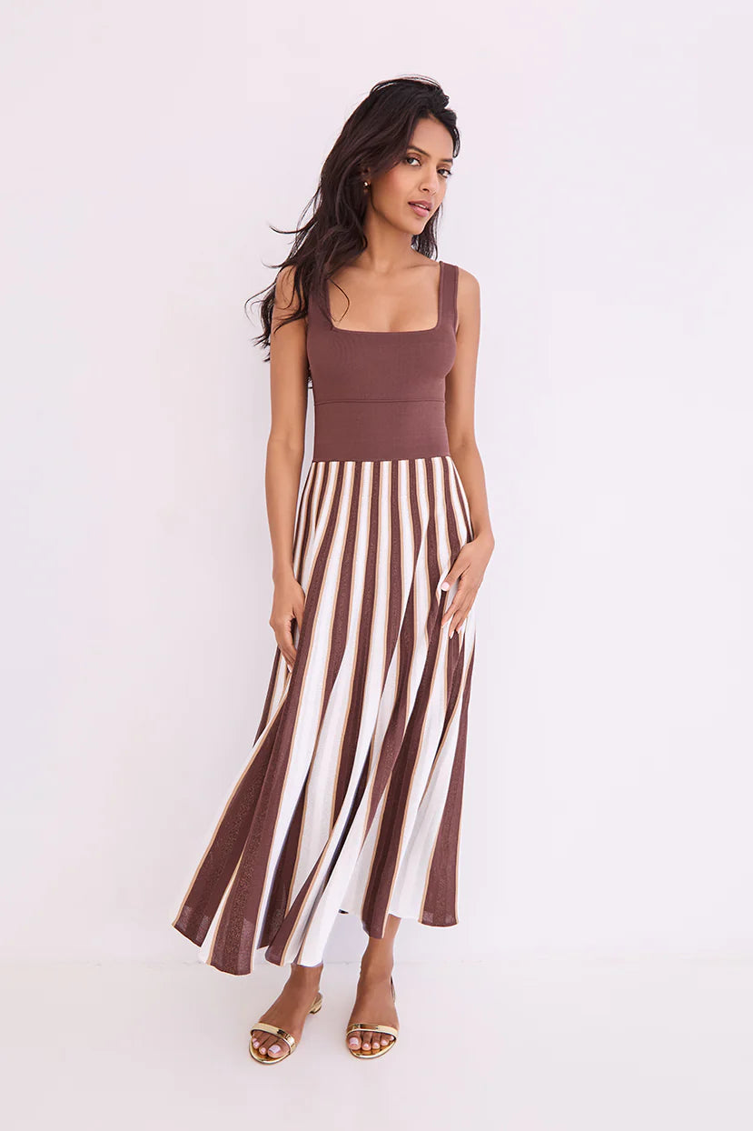 Woman wearing a brown top and striped skirt on a white background