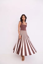 Woman wearing a brown and white striped dress against a white background