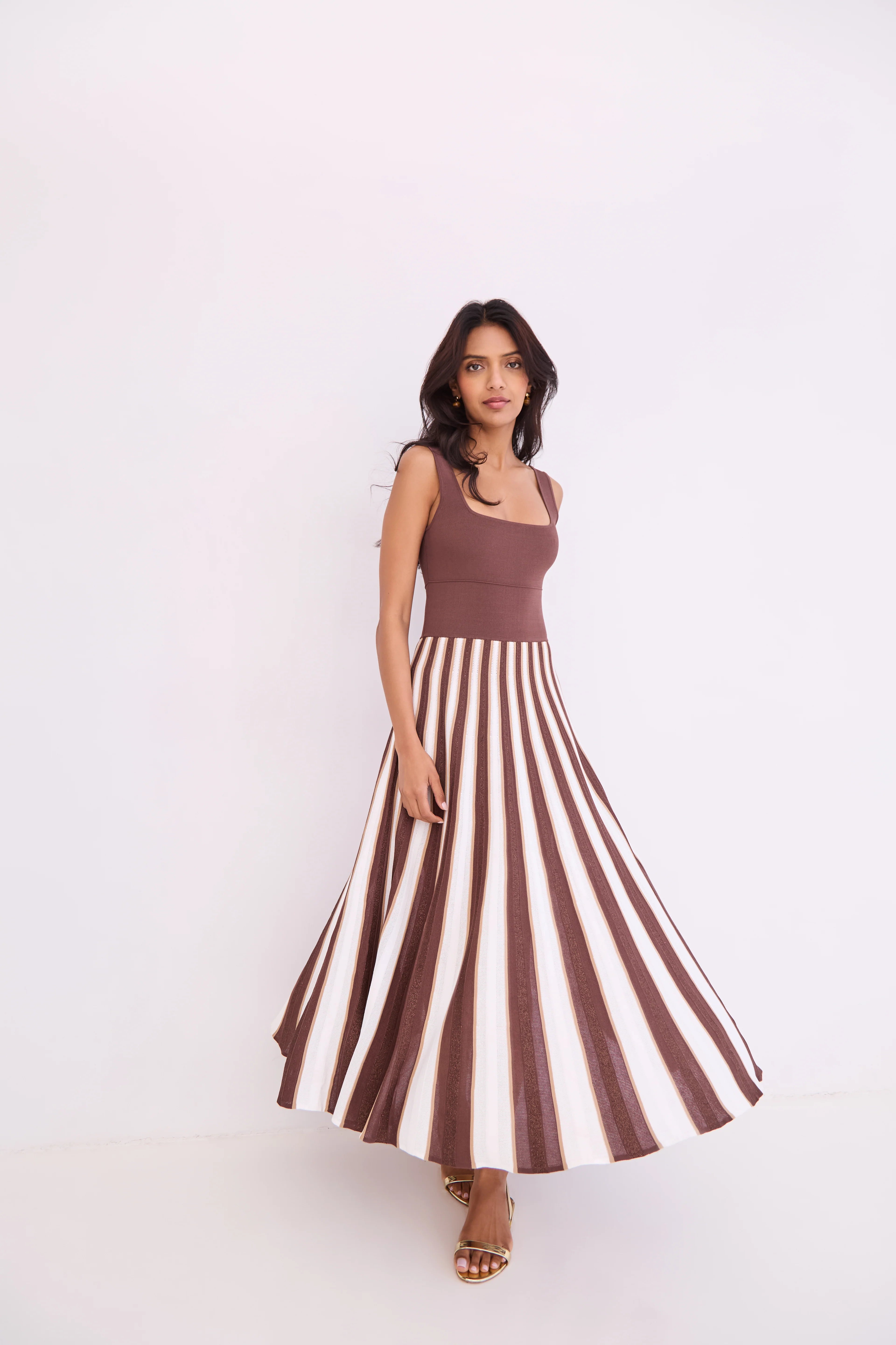 Woman wearing a brown and white striped dress against a white background