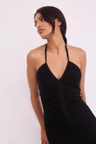 Woman wearing a black halter neck dress against a white background
