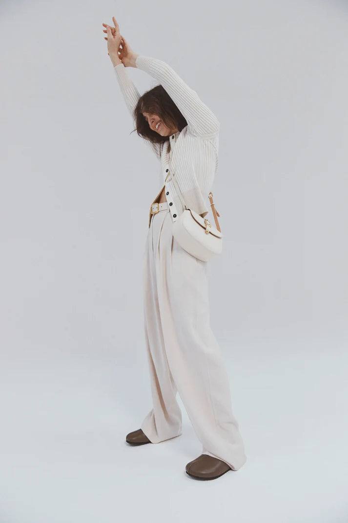 Person wearing a white outfit with a belt on a plain background