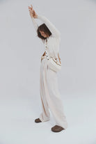 Person wearing a white outfit with a belt on a plain background
