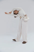 Woman in a white outfit with a white bag on a light gray background