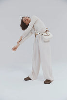 Person wearing a white outfit with a belt on a white background