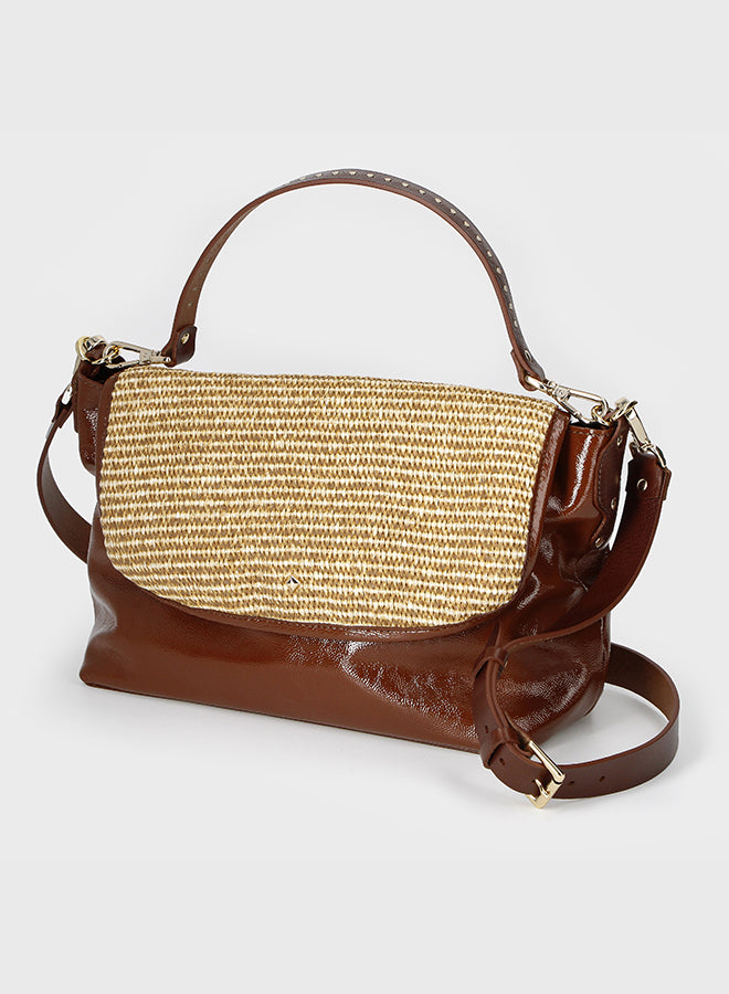 Brown handbag with straw-patterned flap on a light gray background