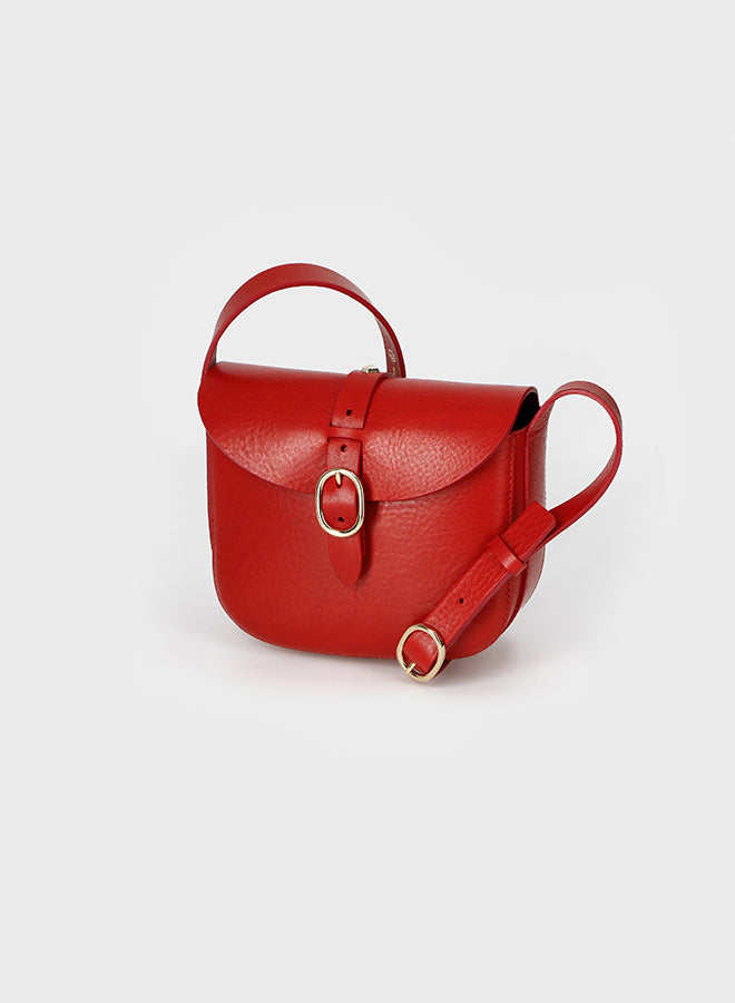 Red leather handbag with a gold ring on a light gray background