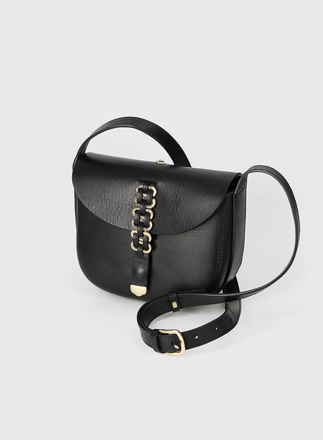 Black handbag with gold chain detail on a light gray background