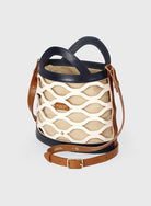 Bucket bag with beige patterned body and brown leather straps on a light gray background