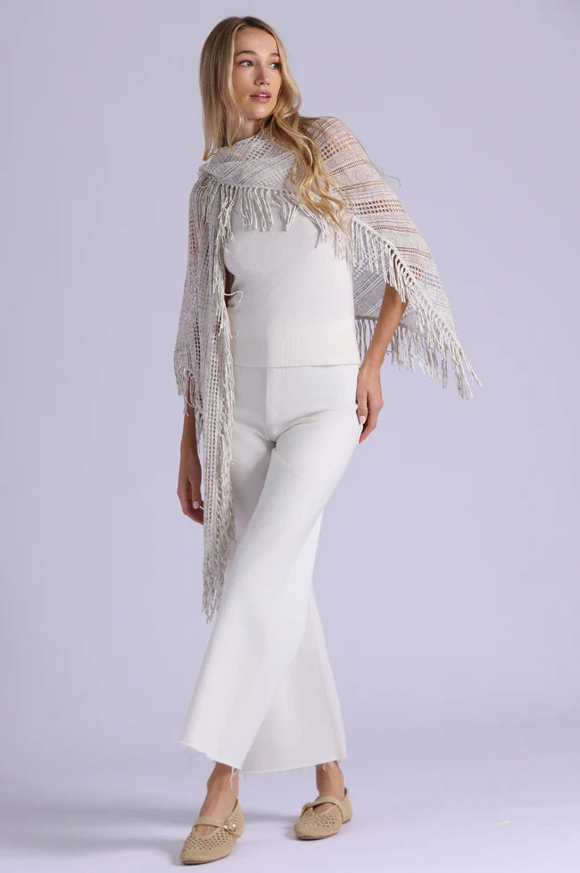 Woman wearing a white outfit with a patterned shawl on a light gray background