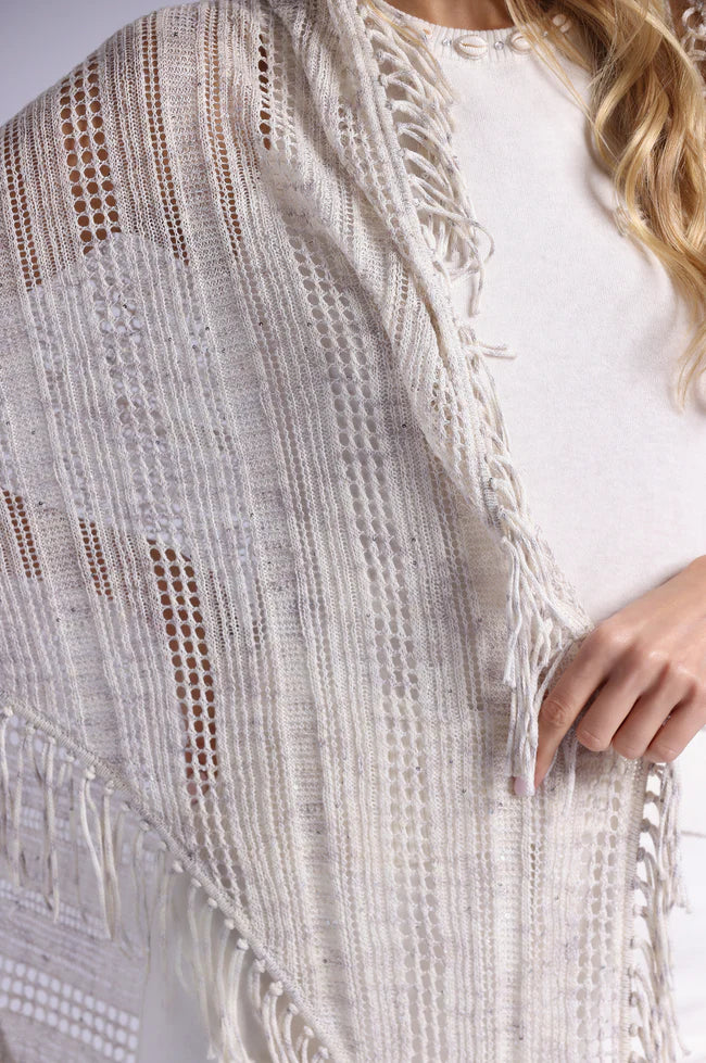 Close-up of a textured beige shawl with fringe details.