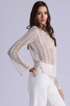 Woman wearing a white lace top and pants on a light gray background