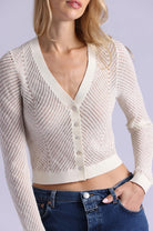 Beige knitted cardigan worn by a person on a plain background
