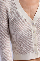 Close-up of a textured beige cardigan with buttons on a plain background