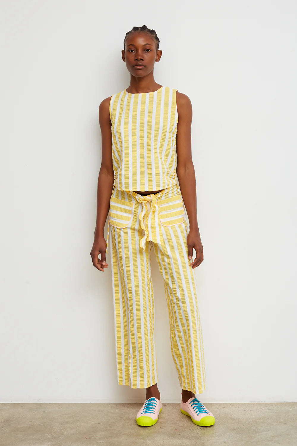 Person wearing a yellow and white striped outfit against a white background