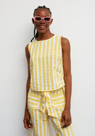 Woman wearing a yellow striped outfit with pink sunglasses against a white background