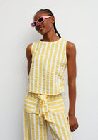 Person wearing a yellow and white striped outfit with pink sunglasses against a white background