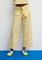 Person wearing yellow and white striped pants with a matching top on a blue and white background