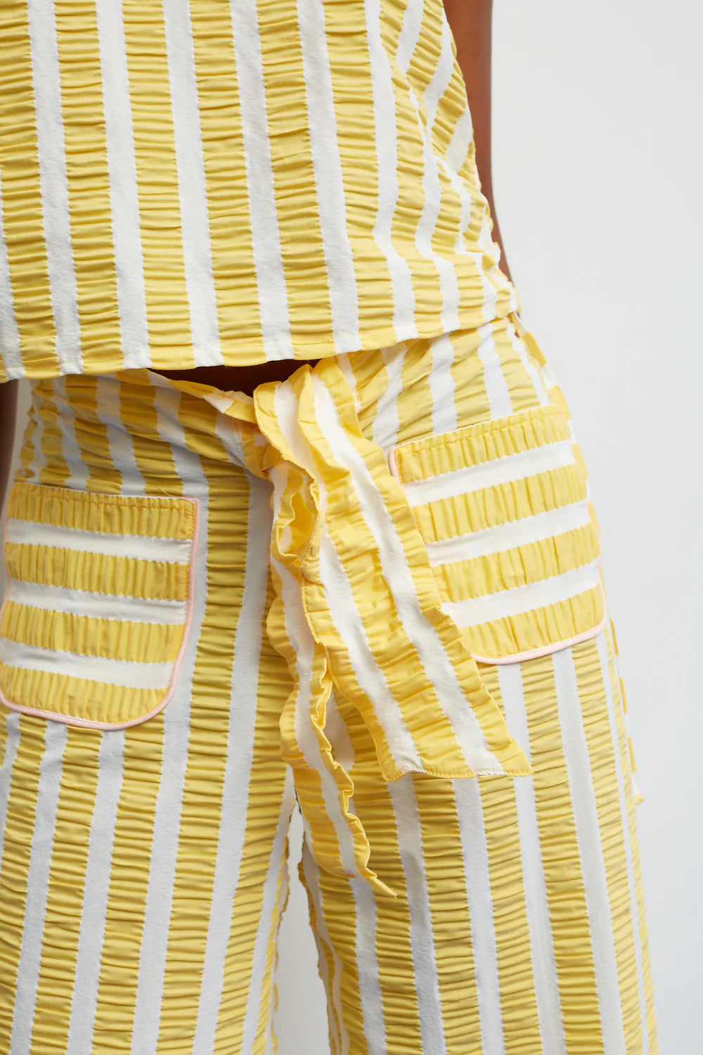 Yellow and white striped outfit with ruffled details on a plain background