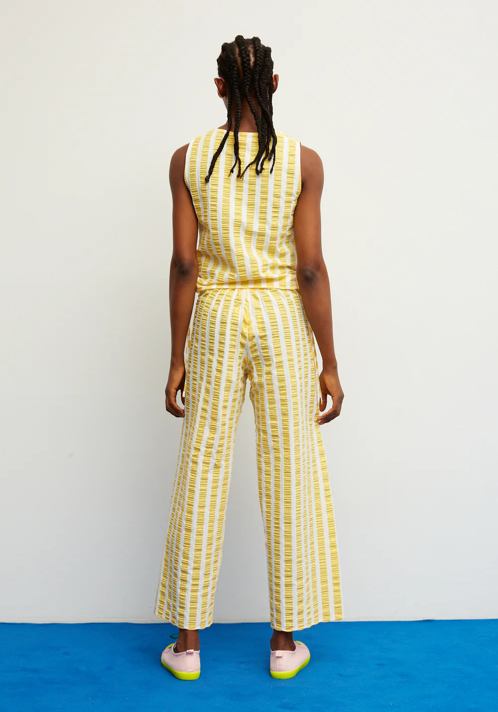 Person wearing a yellow and white striped jumpsuit on a blue and white background