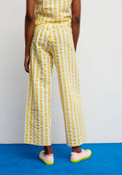 Person wearing a yellow and white striped outfit on a blue platform with a white background