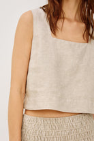 Beige sleeveless top worn by a person on a white background