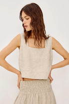 Woman wearing a beige sleeveless top and skirt against a white background