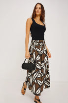 Woman wearing a black top and zebra print skirt with a black handbag on a white background