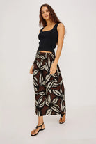 Woman wearing a black top and patterned pants on a white background