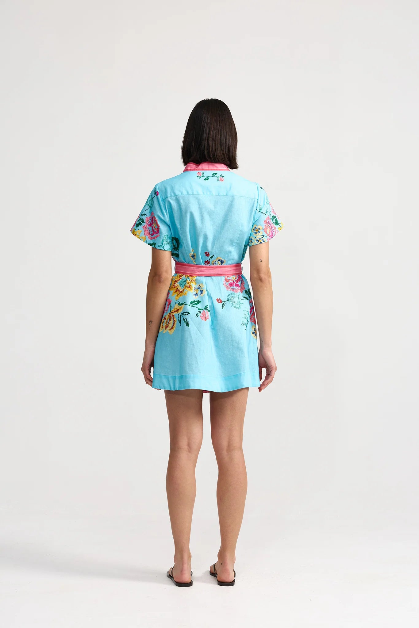 Woman wearing a light blue dress with floral patterns on a white background