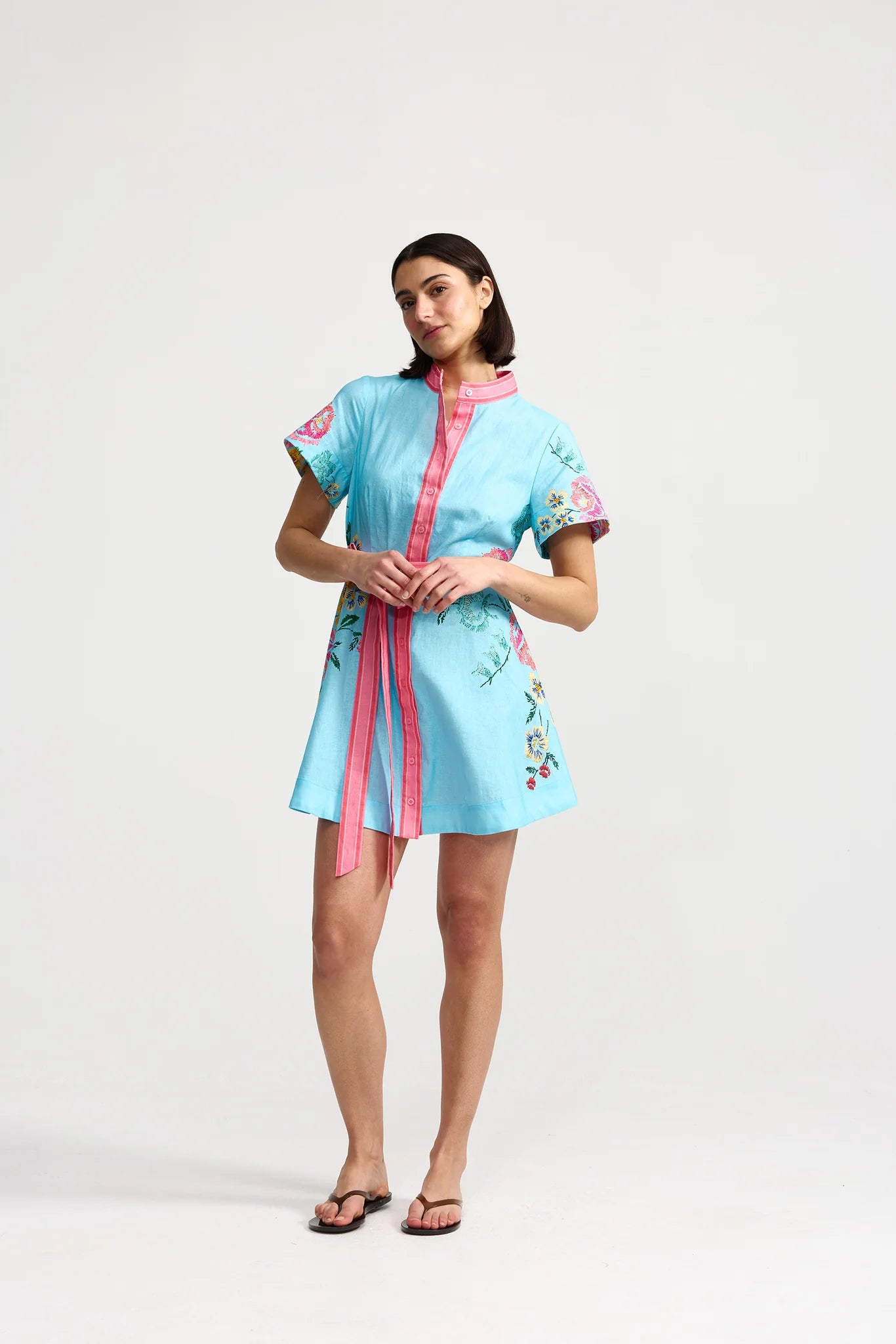 Woman wearing a light blue dress with pink accents on a white background