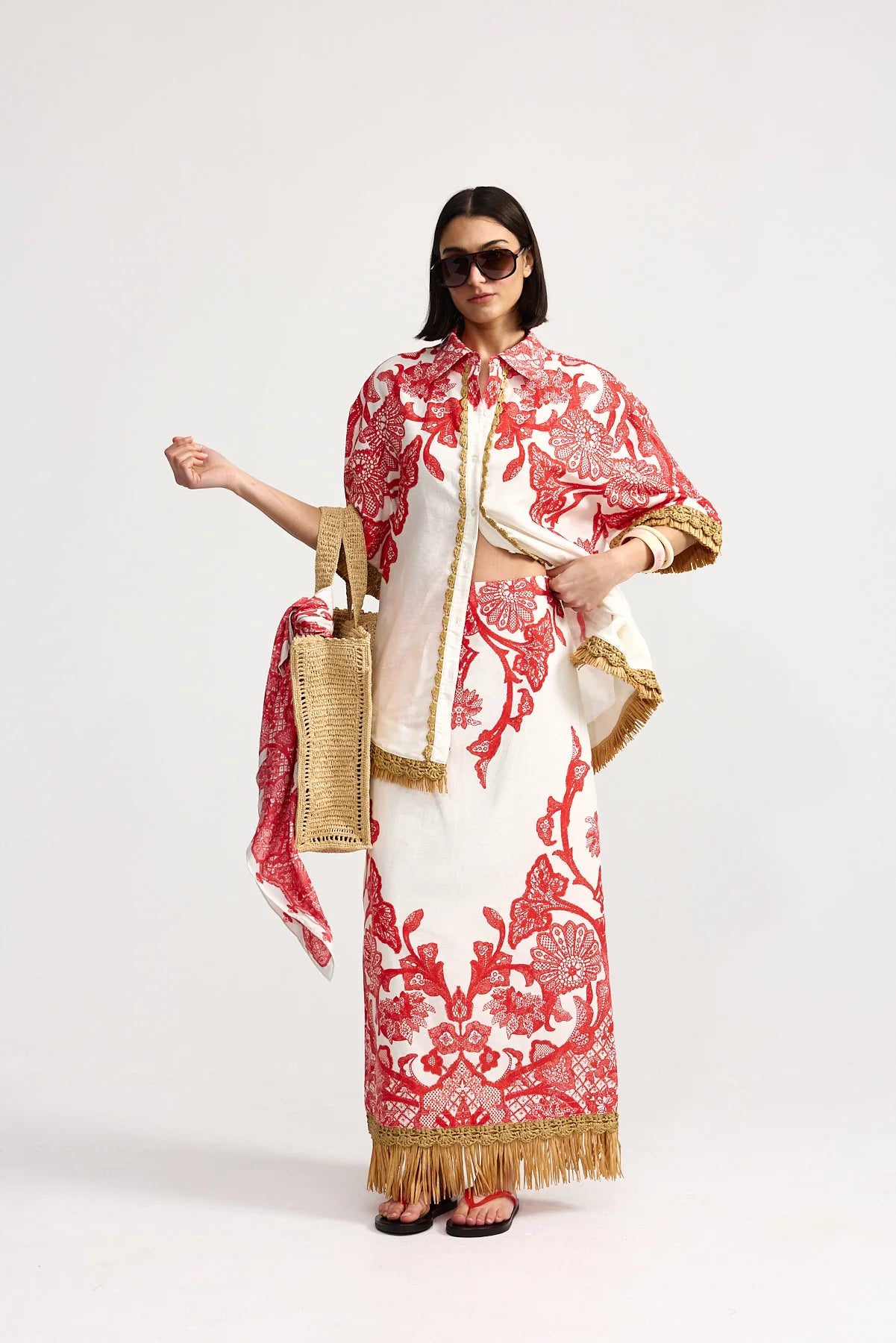 Woman wearing a red and white patterned outfit with gold accents on a white background