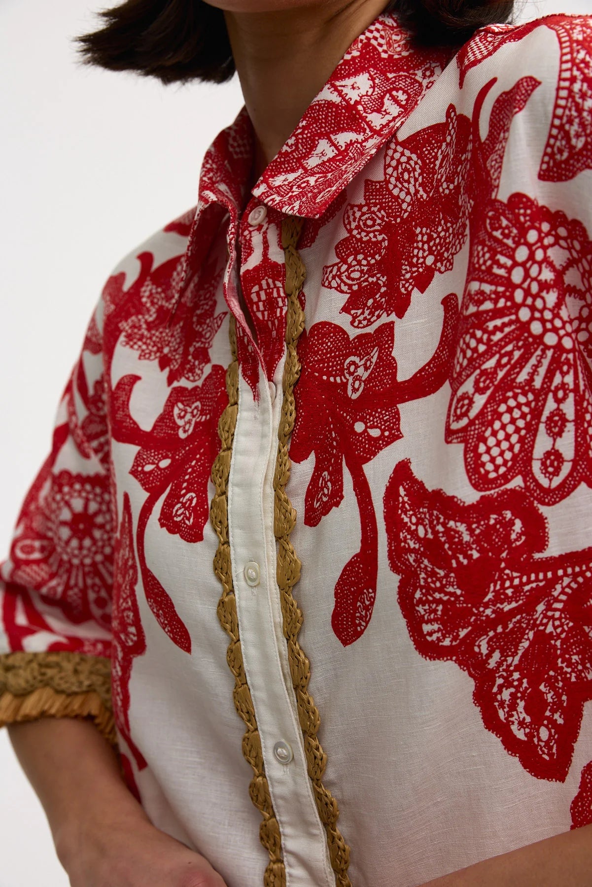 Close-up of a person wearing a red floral patterned shirt with white collar and gold trim.