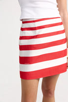 Red and white striped skirt worn by a person on a plain background