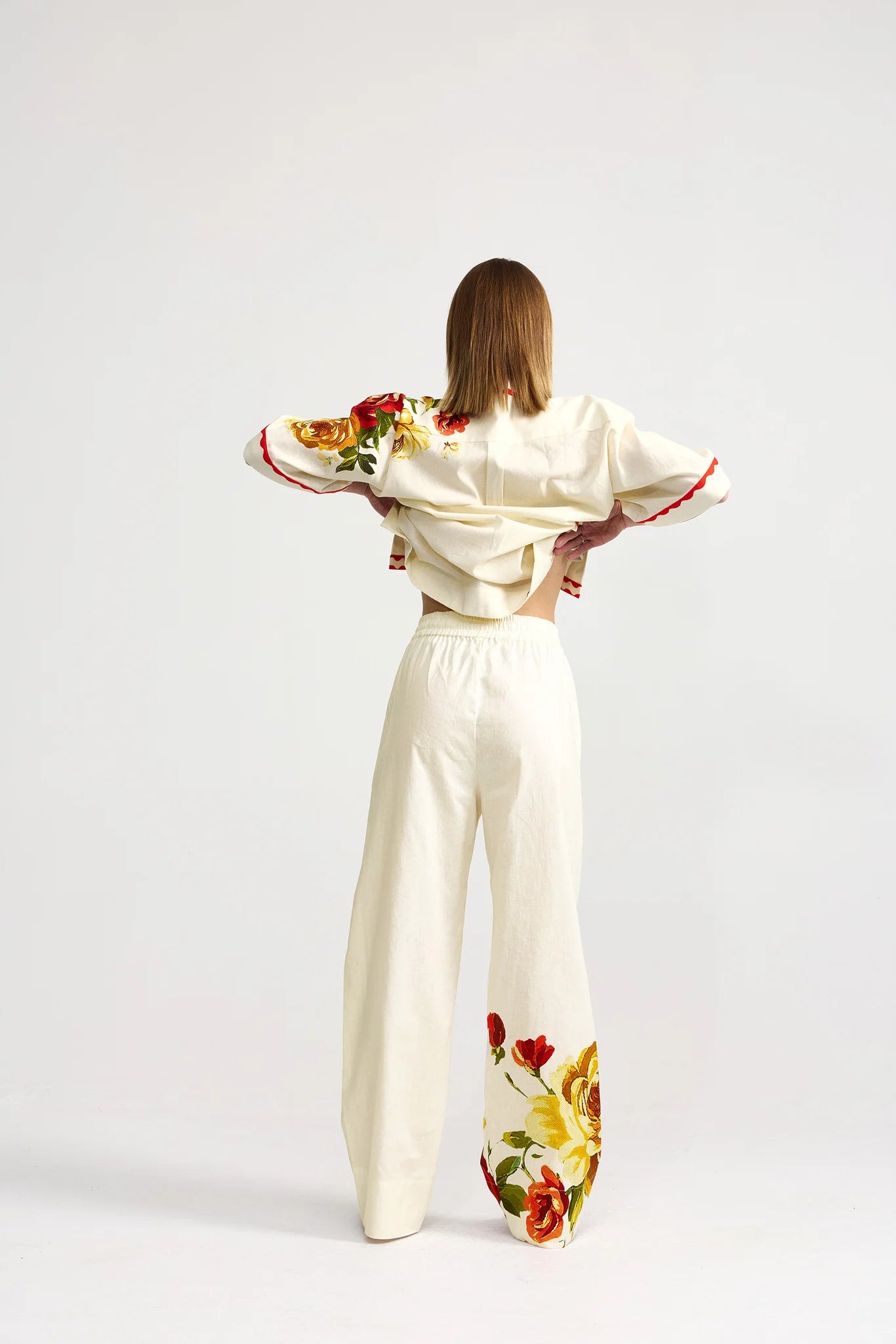 Woman wearing a cream-colored outfit with floral designs on a white background