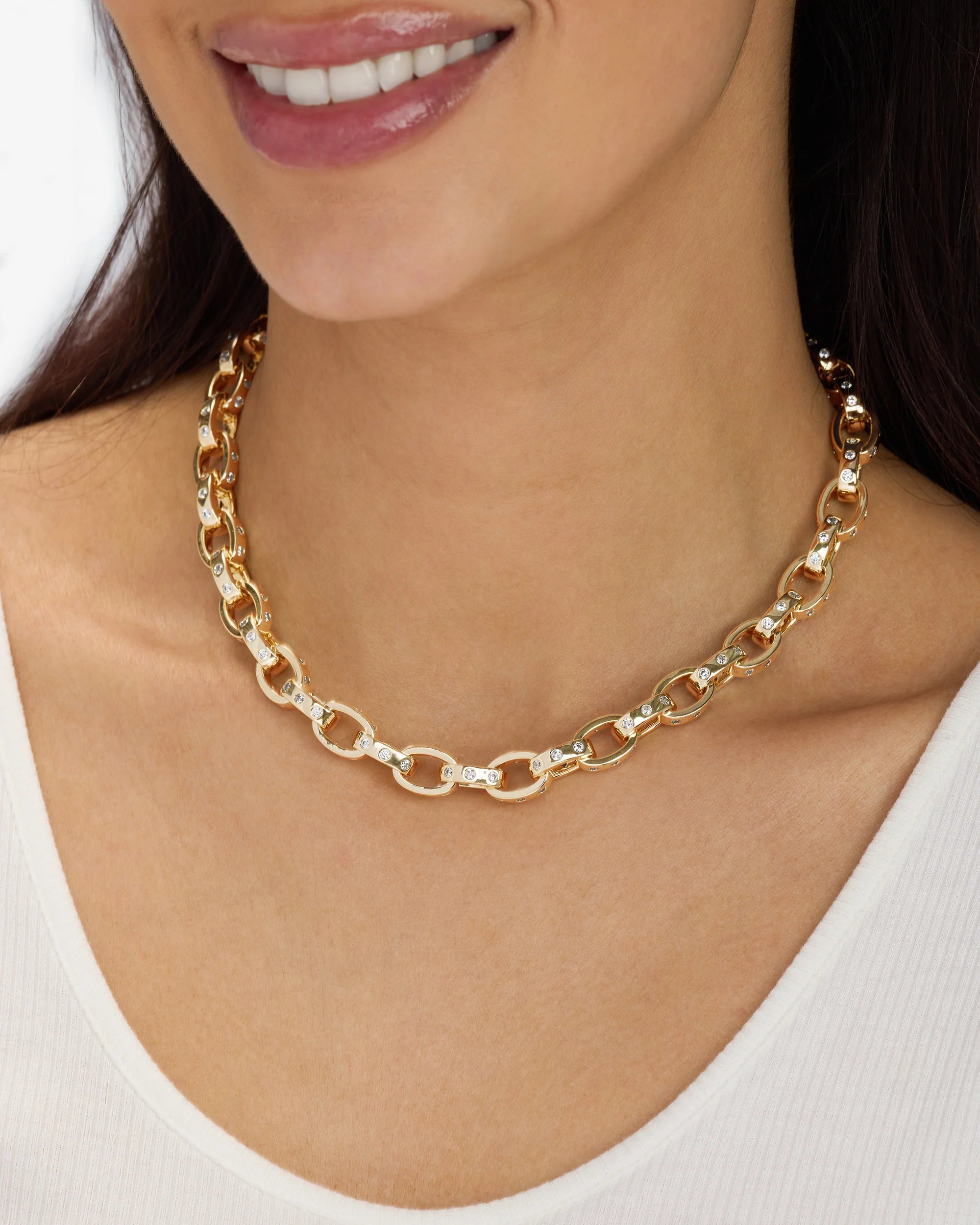 Gold chain necklace worn by a person with a white background