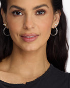 Close-up of a woman wearing hoop earrings with a plain background