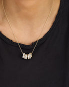 Gold necklace with a pendant on a person wearing a black top
