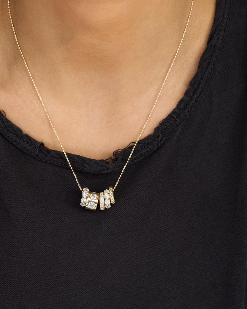 Gold necklace with a pendant on a person wearing a black top