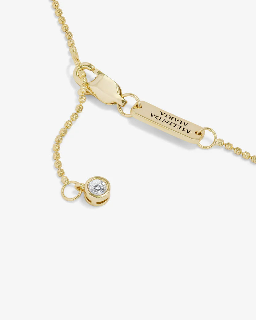 Gold bracelet with a diamond charm on a white background