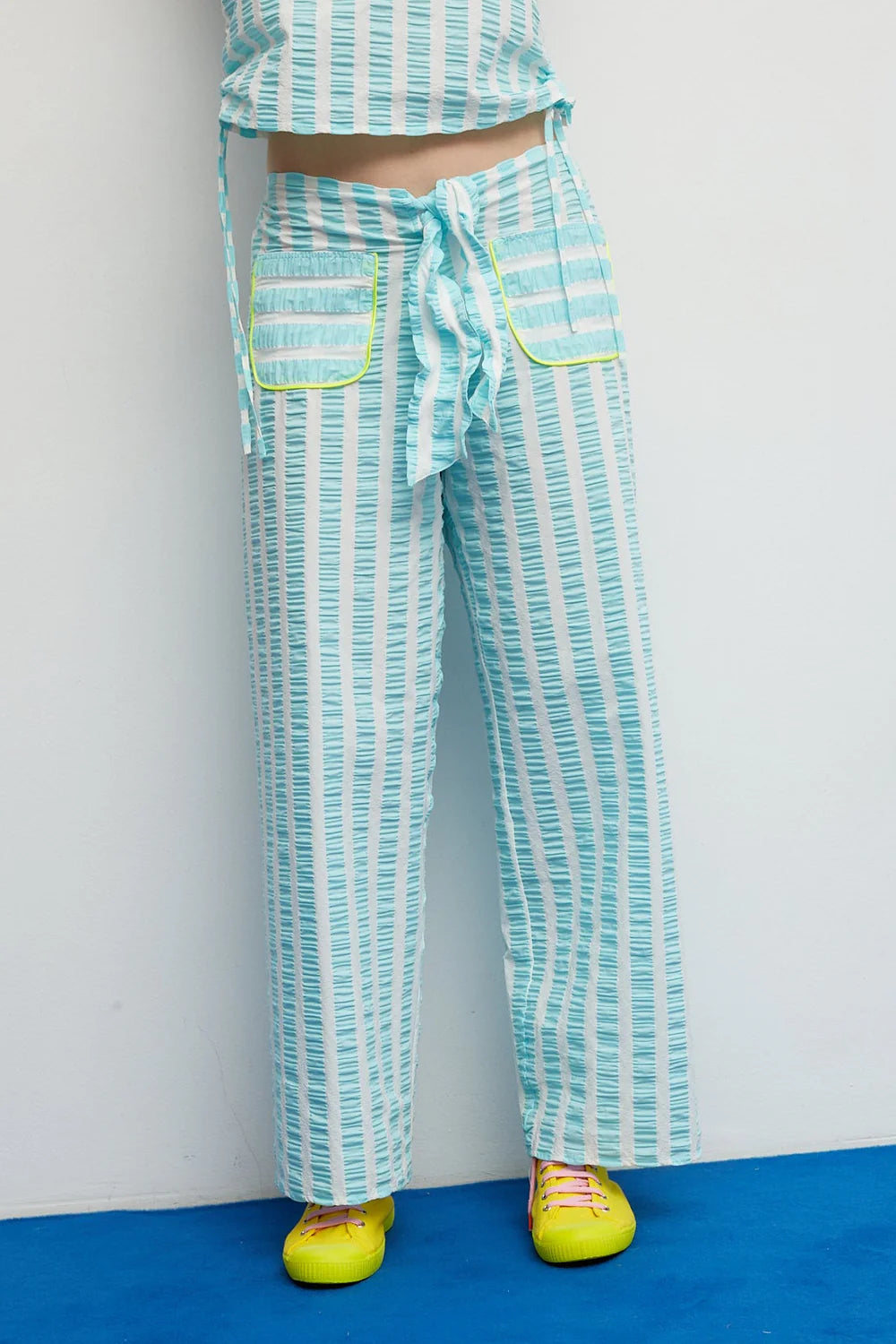 Person wearing a green and white striped outfit with yellow shoes on a blue and gray background